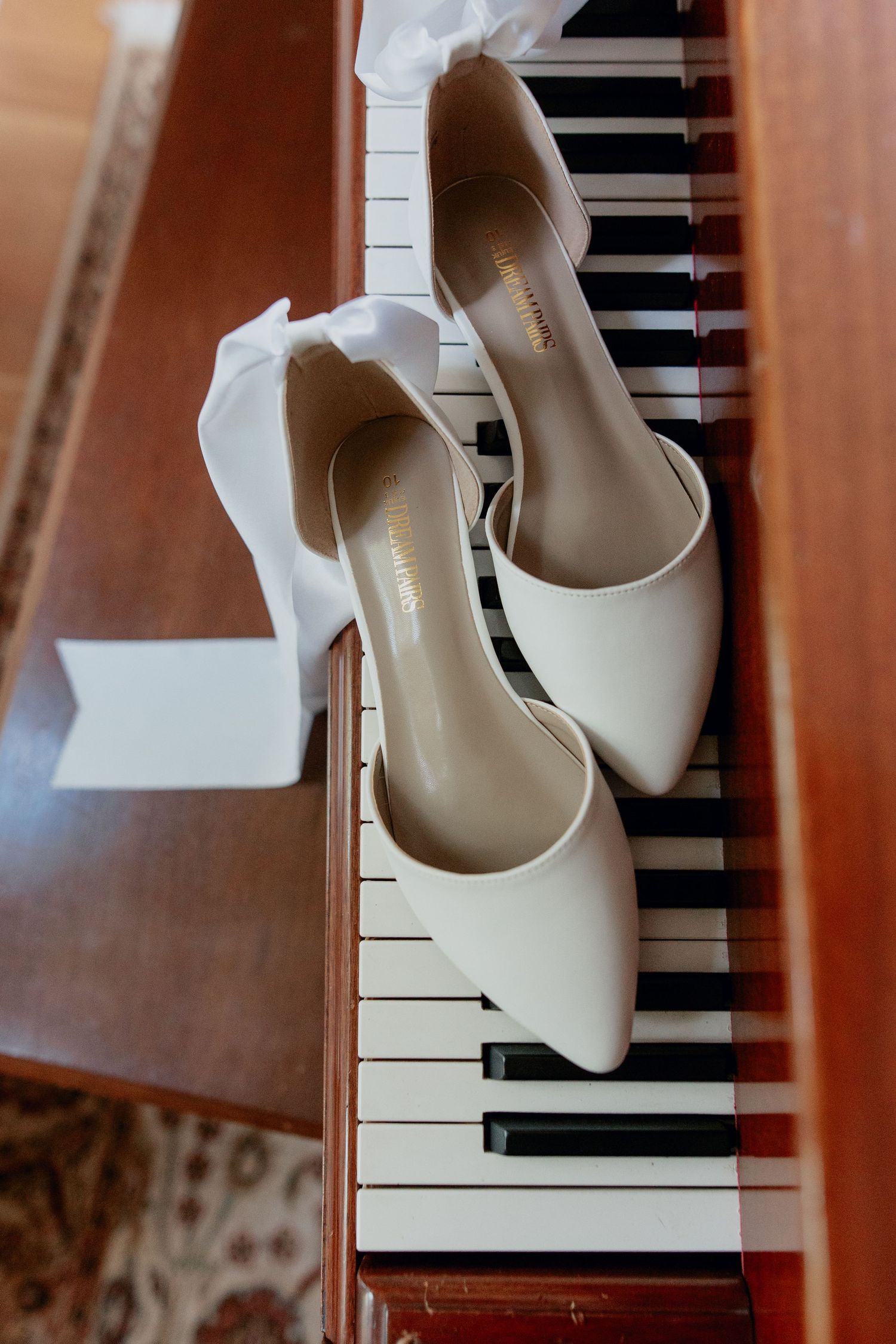 White bridal heels elegantly placed on piano keys, creating a romantic wedding day detail shot.