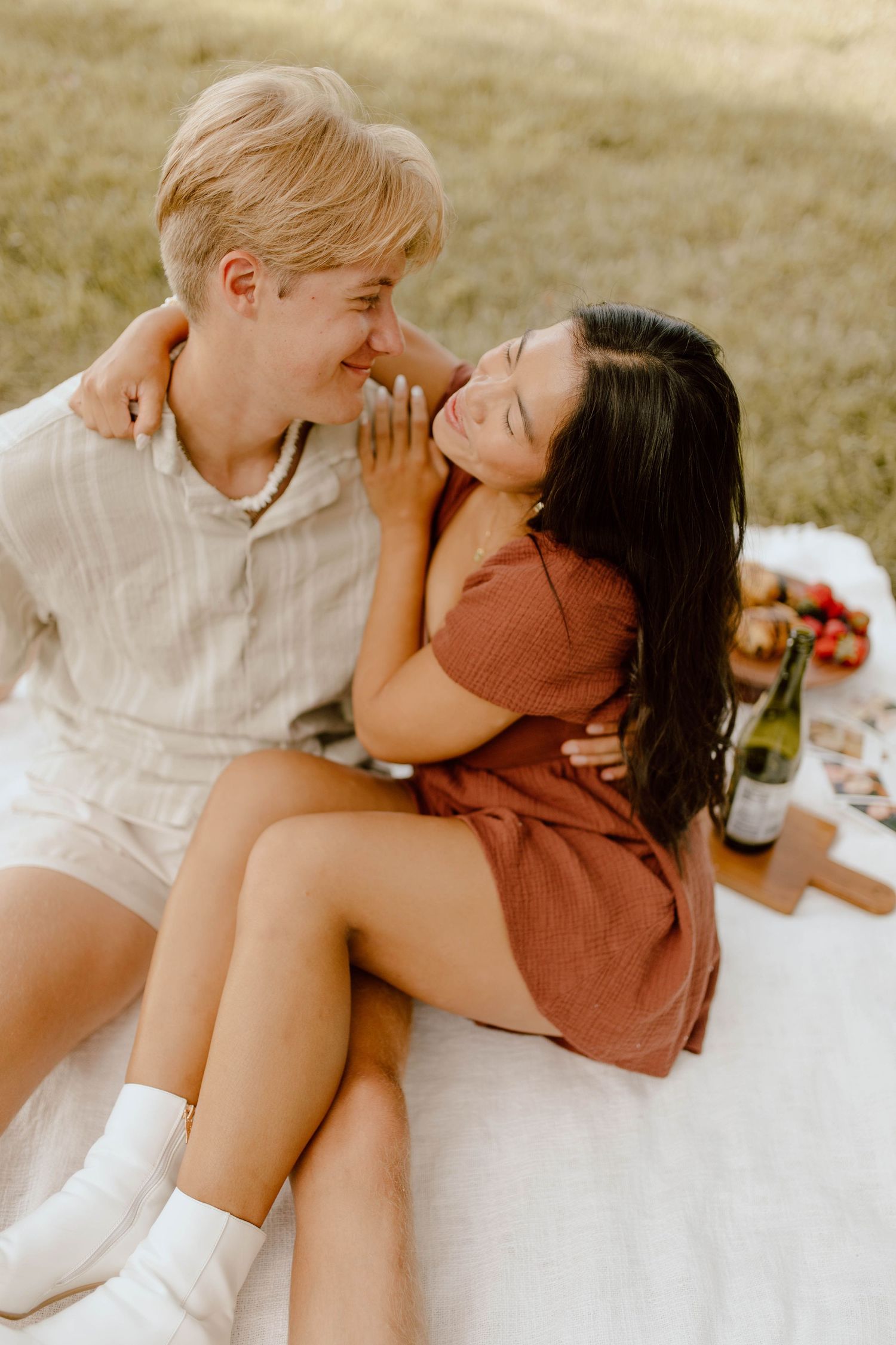 A romantic picnic scene on a blanket with a couple sharing an intimate moment.