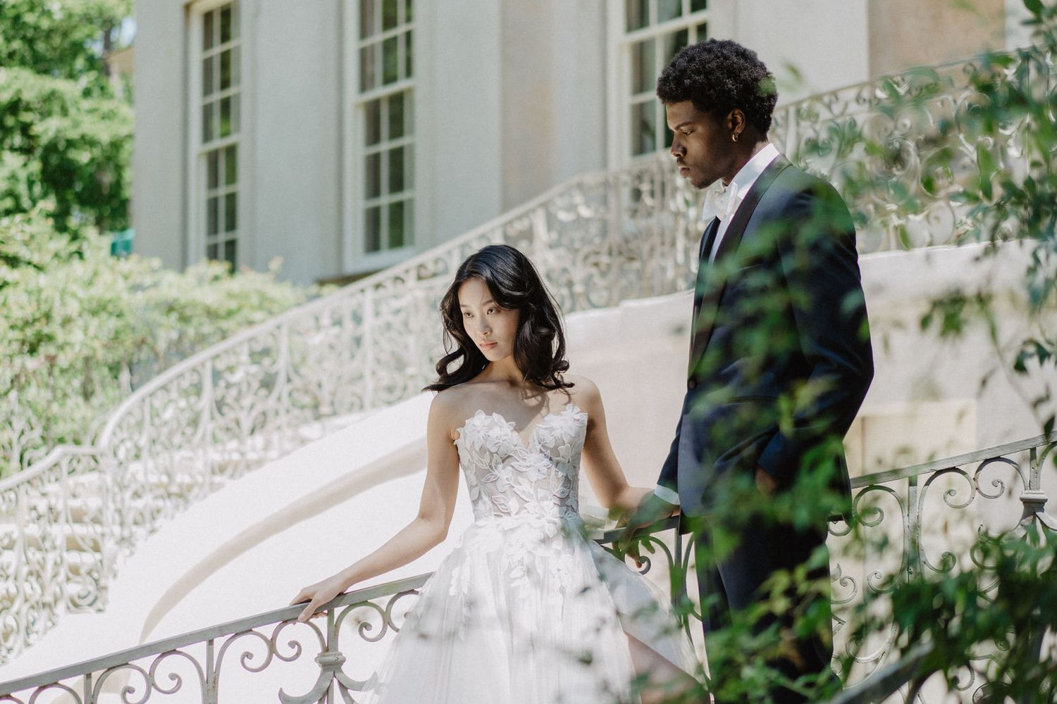 A romantic wedding portrait on an elegant staircase with ornate railings.