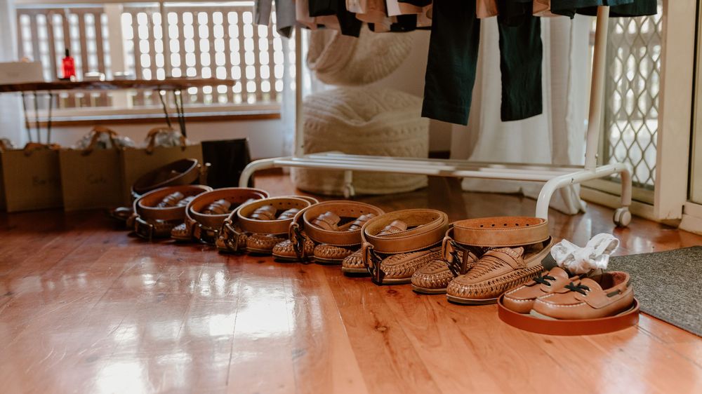 A row of brown leather dress shoes lined up on a wooden floor for a wedding party.