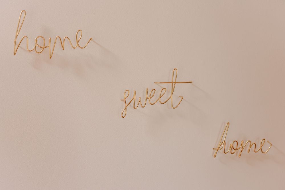 Gold wire 'home sweet home' wall art text against neutral background.