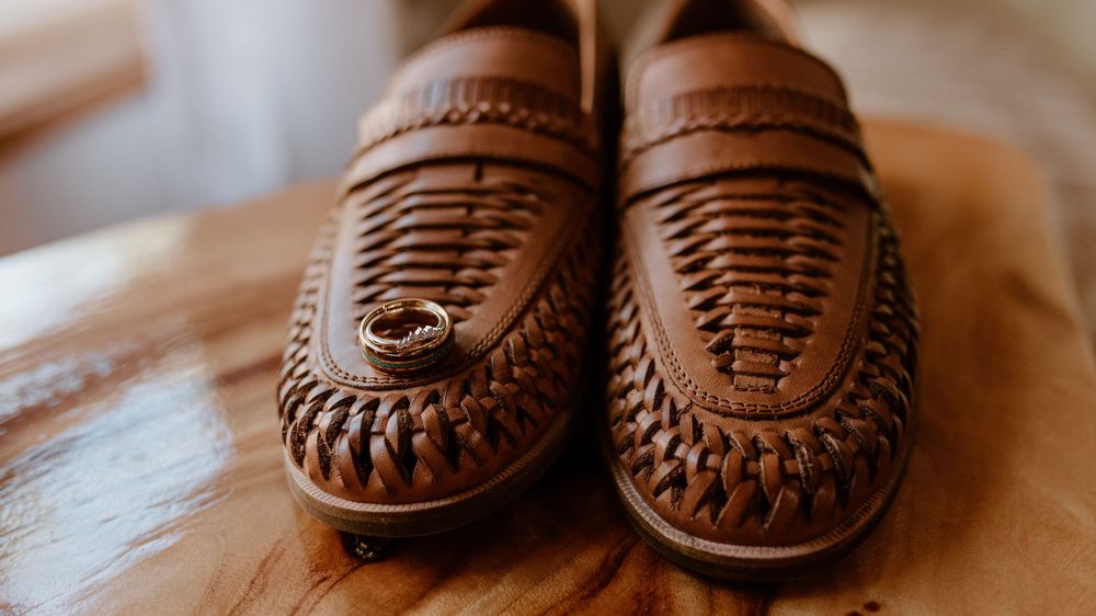 A pair of brown leather loafers with intricate woven details displayed on a light surface.