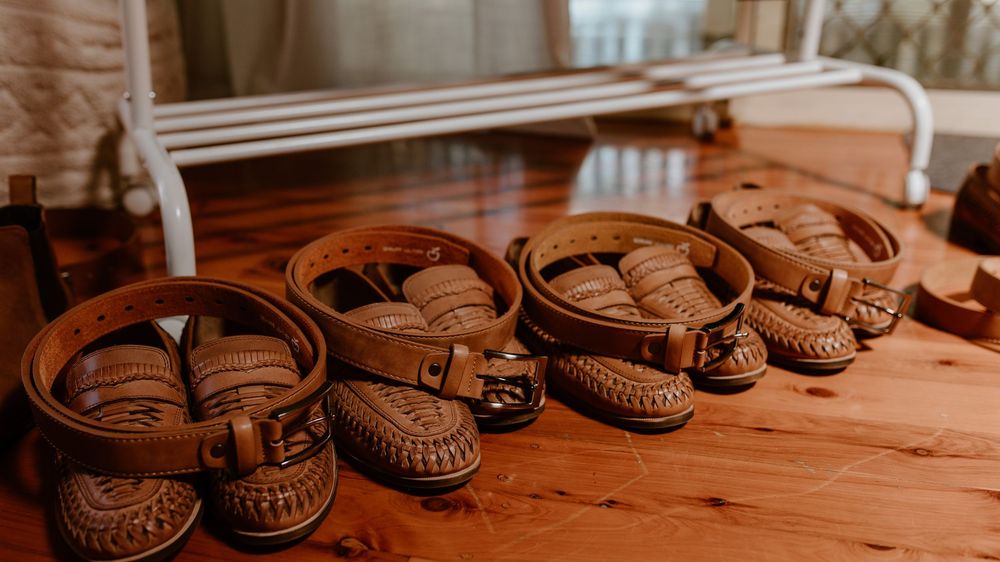 A row of brown leather dress shoes arranged on a wooden bench.