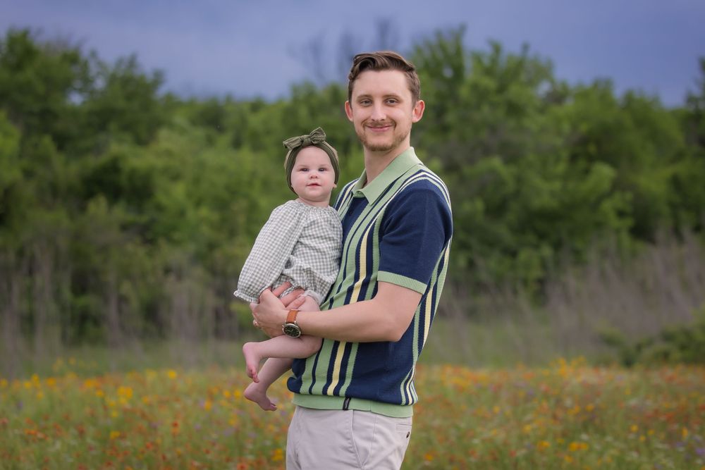 Parent and child standing together in a wildflower field wearing green and white striped clothing.