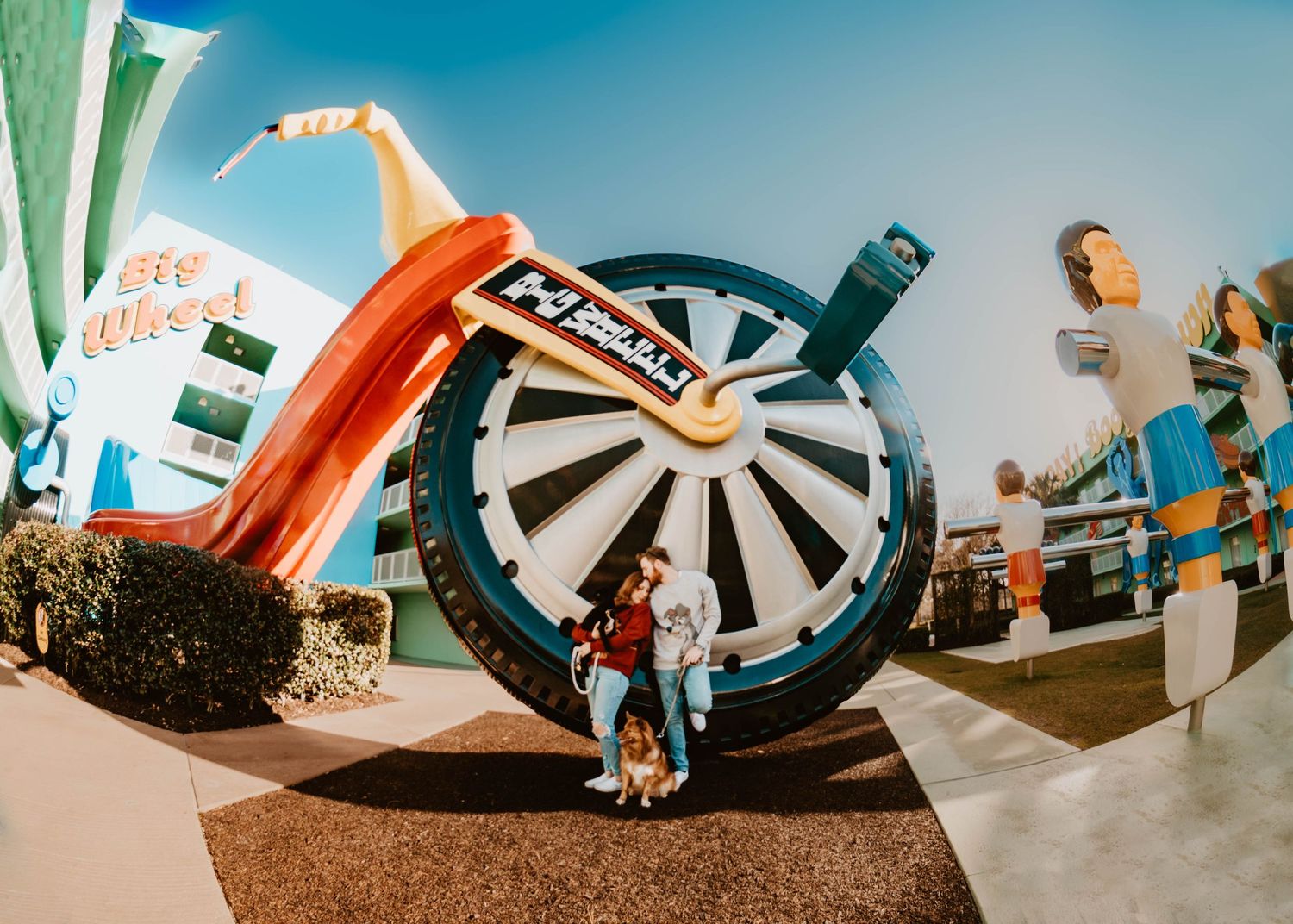 John & Emily anniversary photos at Disney's Pop Century Hotel with the Big Wheel & their dogs. Cred: LexTakePix