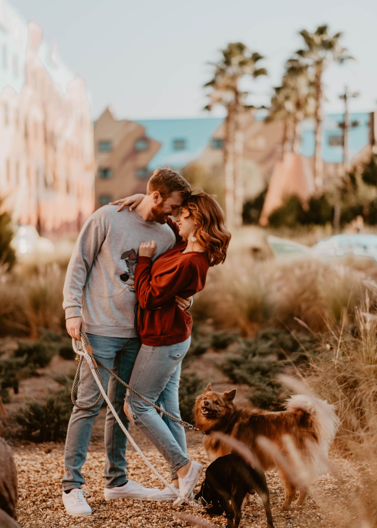 John & Emily anniversary photos at Disney's Art of Animation with Cozy Cone Motel in background & their dogs. Cred: LexTakePix