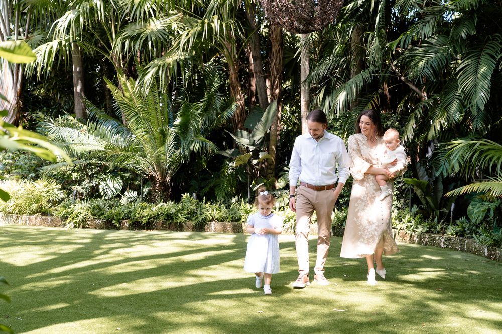 Elegant wedding celebration scene in a lush tropical garden setting with palm trees and natural greenery in the background.