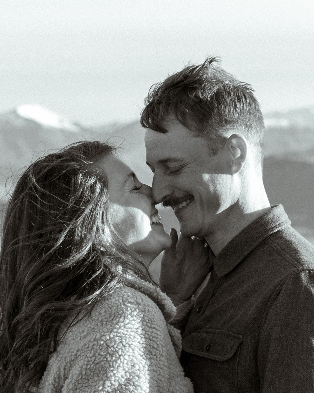 A romantic black and white portrait captures an intimate moment between a couple sharing a tender smile.
