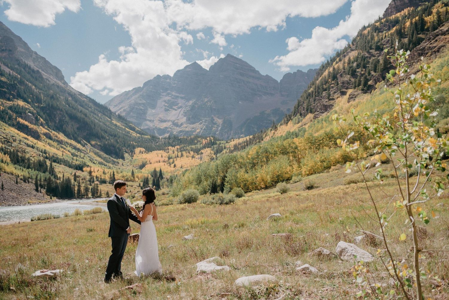 A newlywed couple celebrates their marriage against a scenic backdrop of rugged mountain peaks at Maroon Bells, Colorado.
