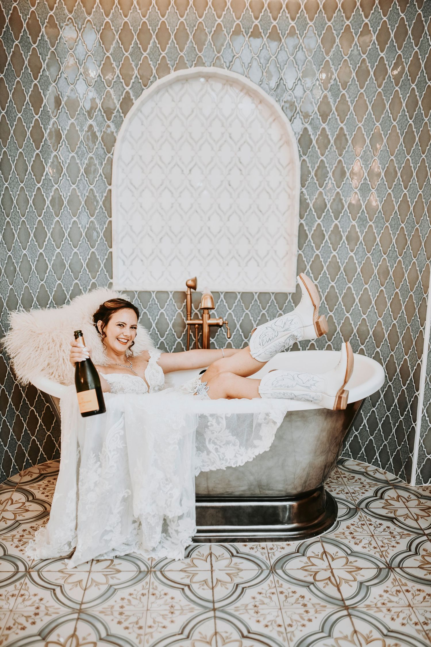 Bride in cowgirl boots smiling in metal bathtub