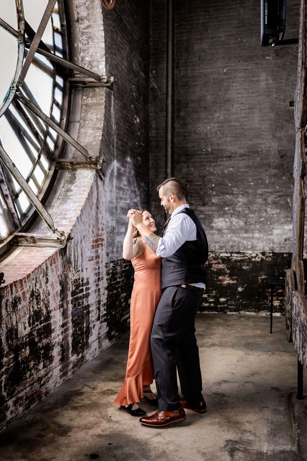 Couple dancing in vintage industrial space with exposed brick walls and windows.