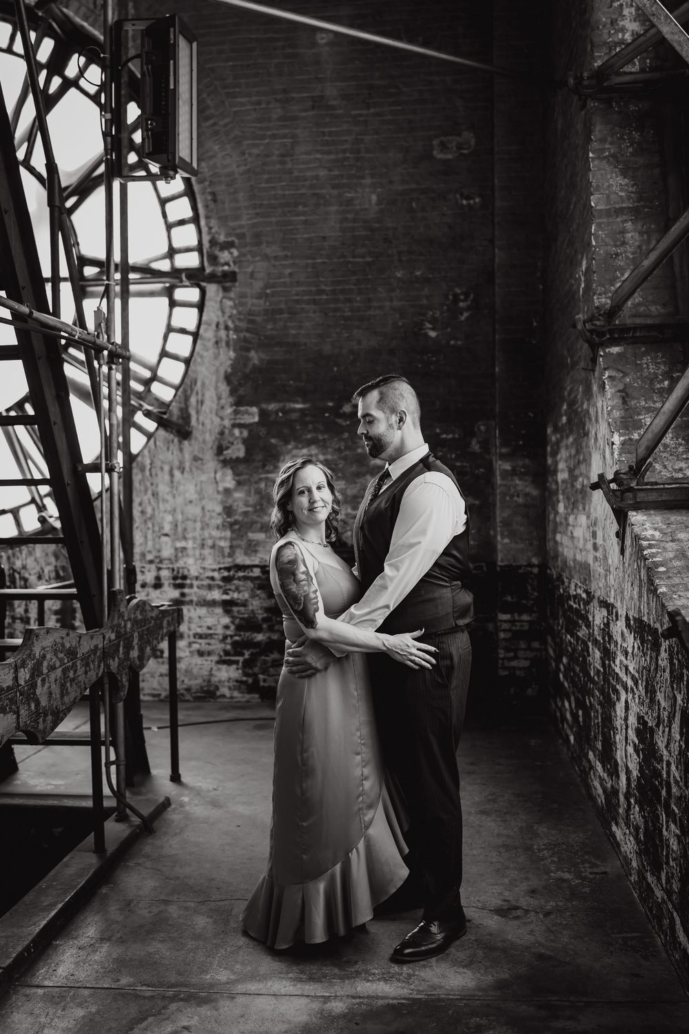 Romantic couple shares tender moments in moody black and white photos against rustic brick walls.