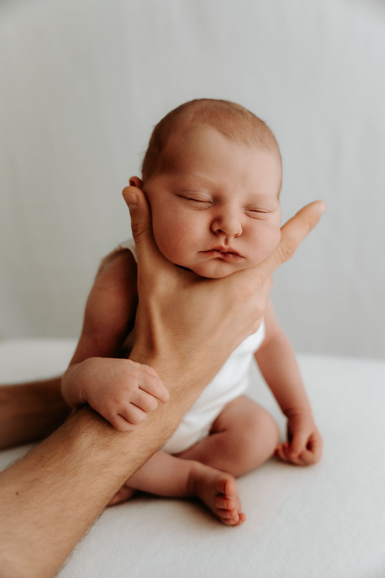 Close-up photos of an infant in white clothing against a light background.