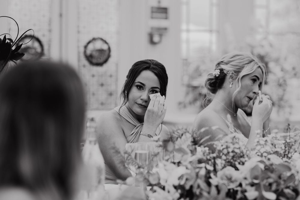 Black and white candid shots of a couple smiling and embracing in a greenhouse surrounded by flowers and plants.