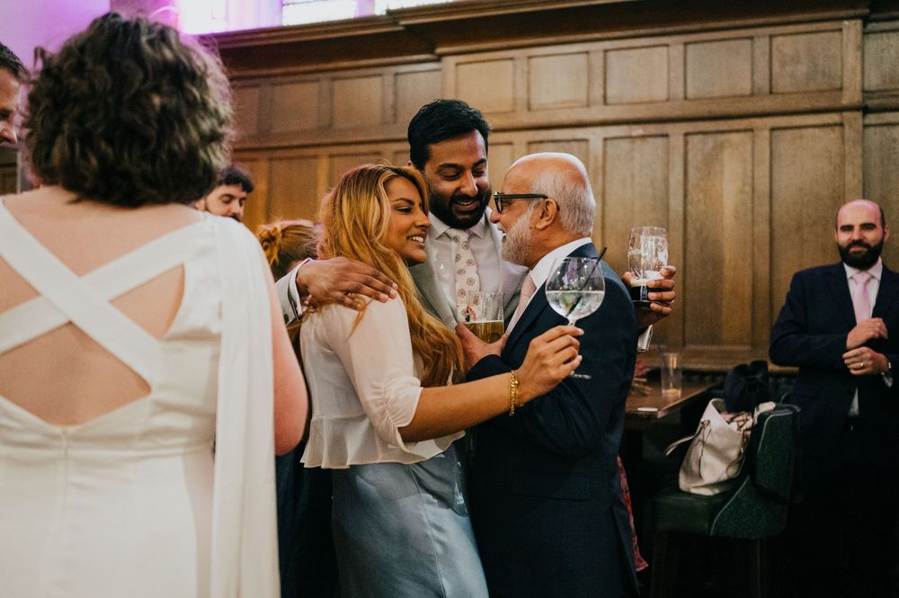 Loving embraces shared between guests during an emotional moment at an elegant wedding reception in a wood-paneled venue.