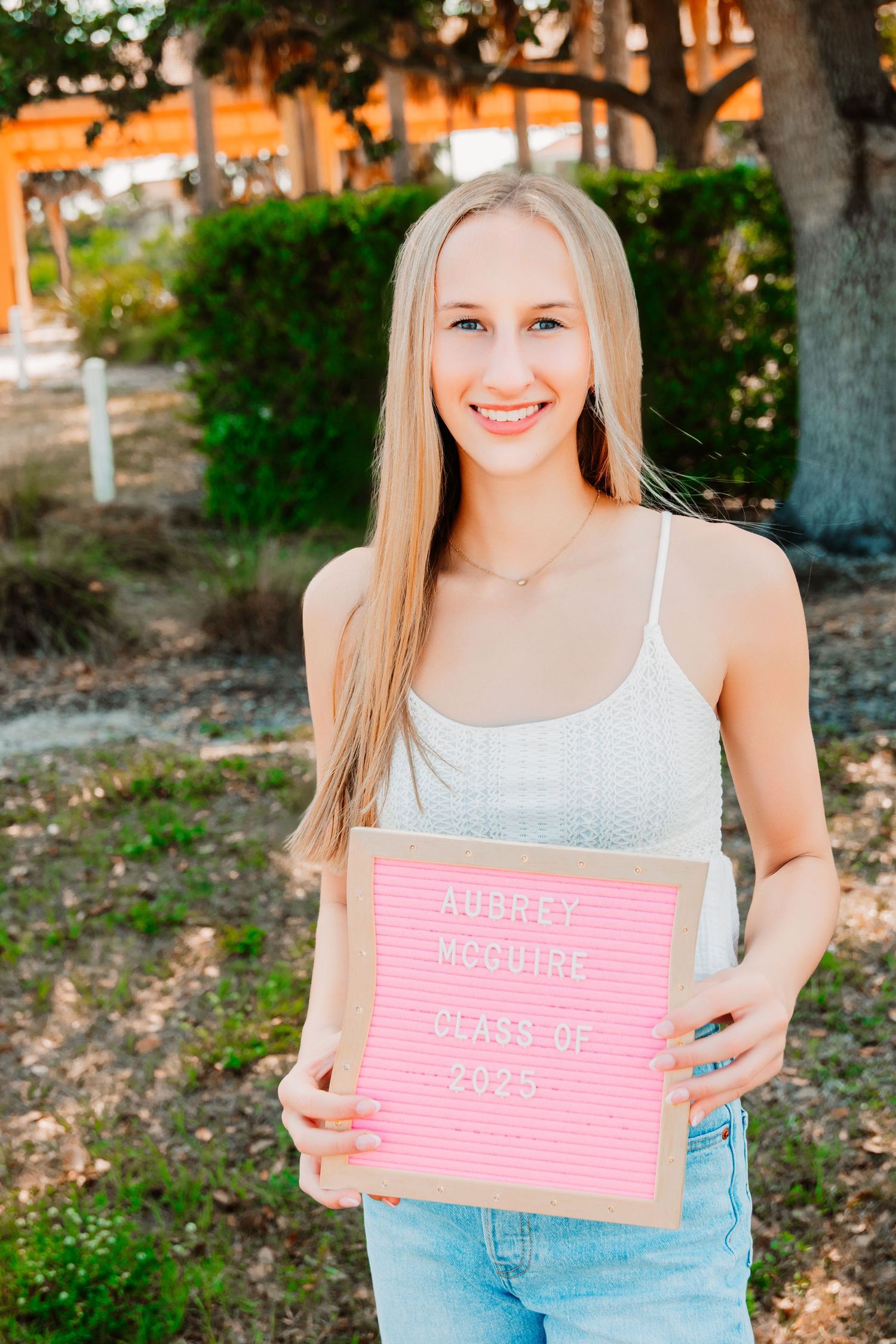 senior girl holding a letterboard with future plans displayed.