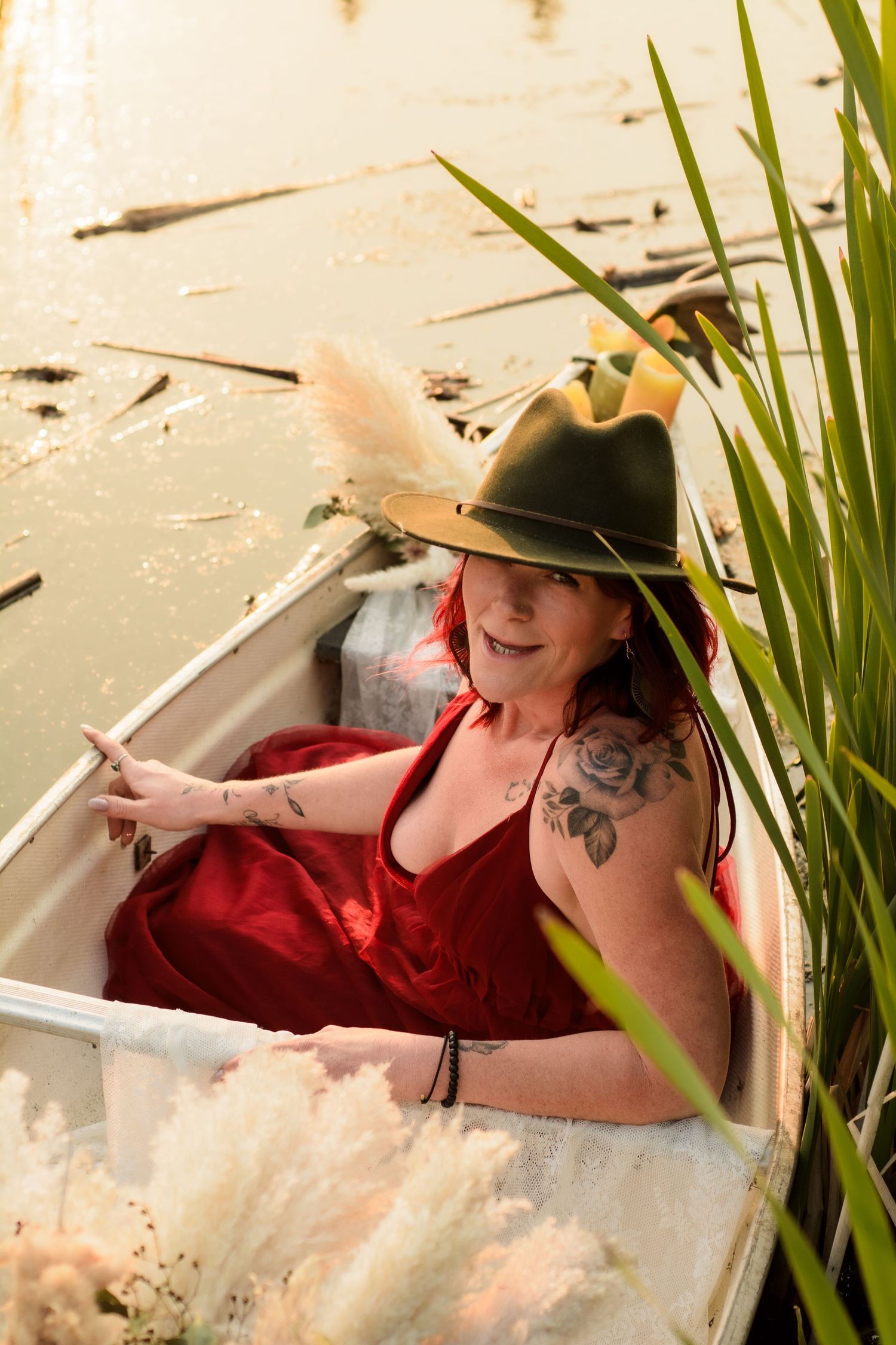 Someone in a red dress lying in a rowboat on the water near green reeds, captured in a series of photos.