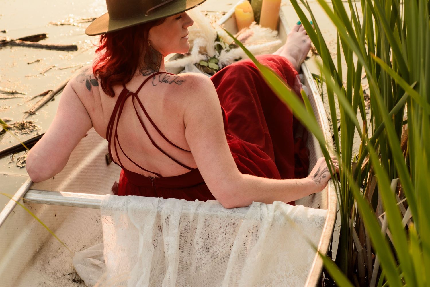 A person in a floral dress and hat sits and takes notes in a lush outdoor garden setting.