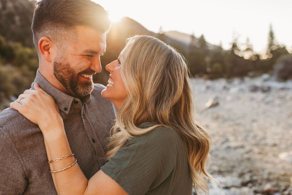 A loving couple embraces and shares an intimate moment together during golden hour sunlight in a scenic outdoor setting.