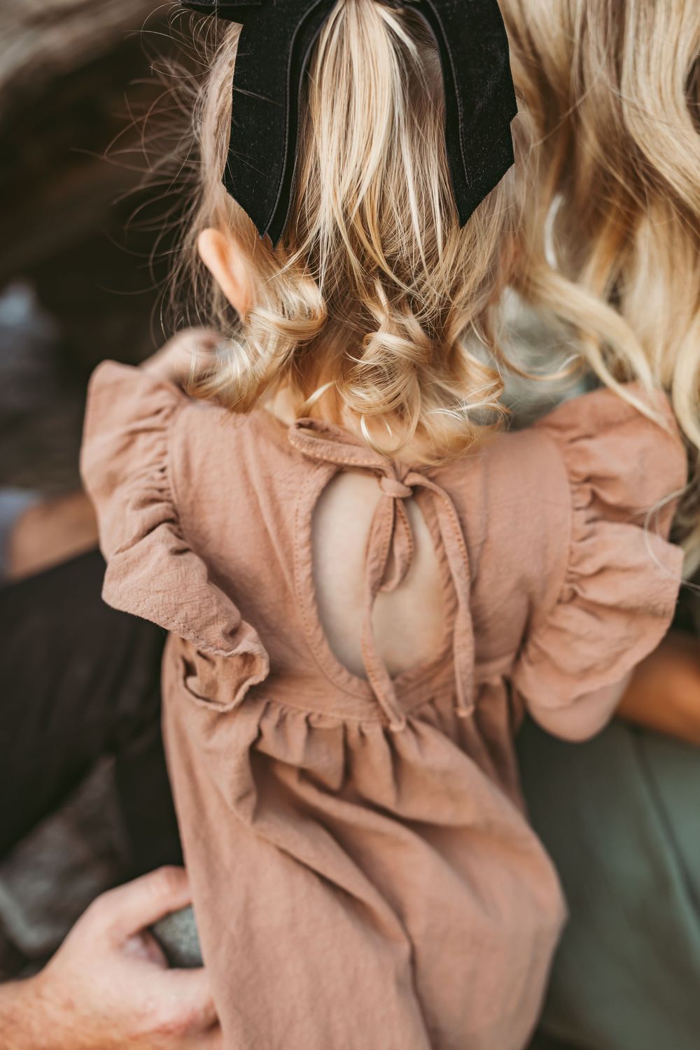 Close up view showing soft pink ruffled dress details under golden light.