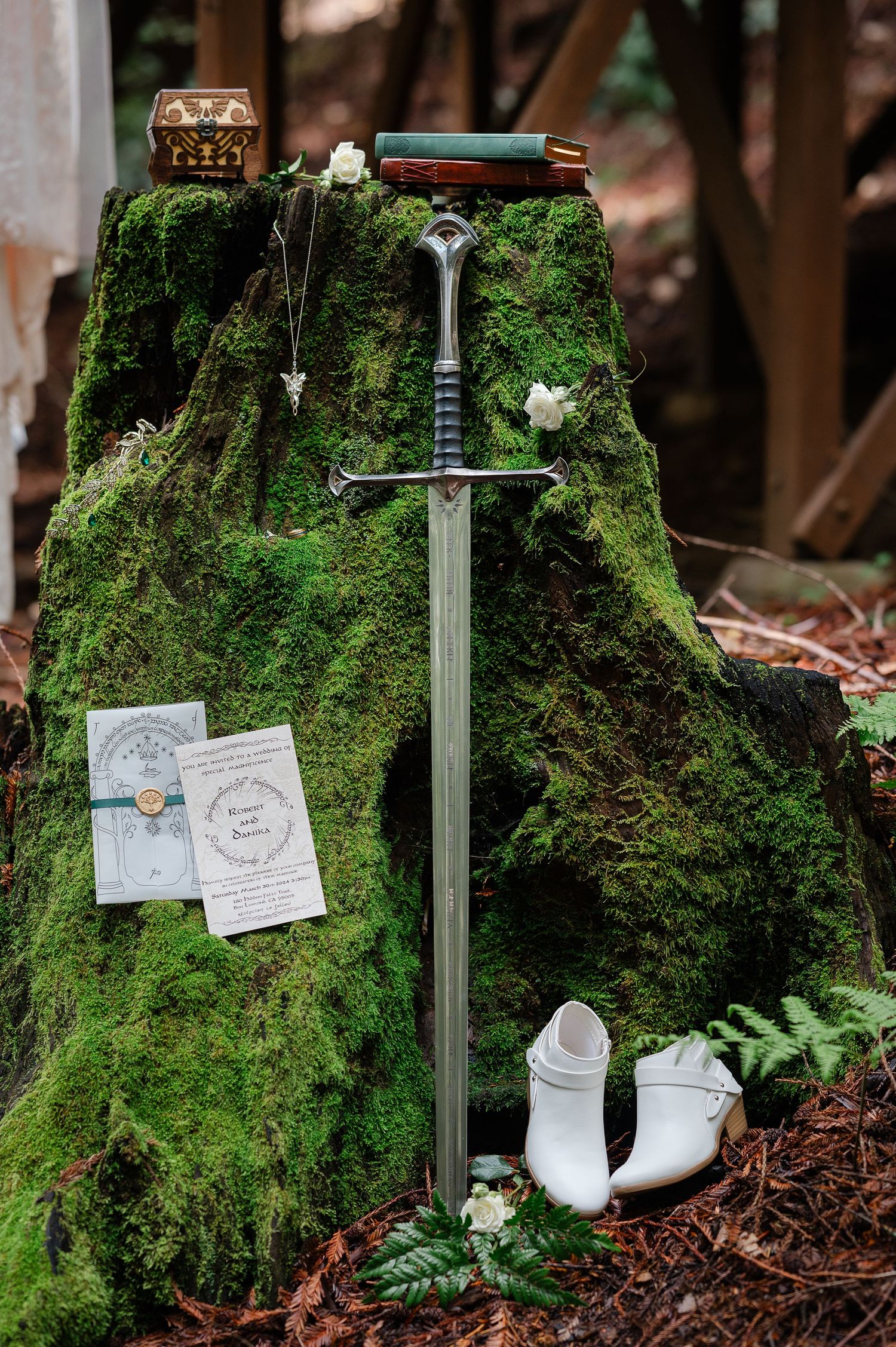 A white wedding dress hangs elegantly against rustic wooden cabin posts in a forest setting with moss-covered ground.