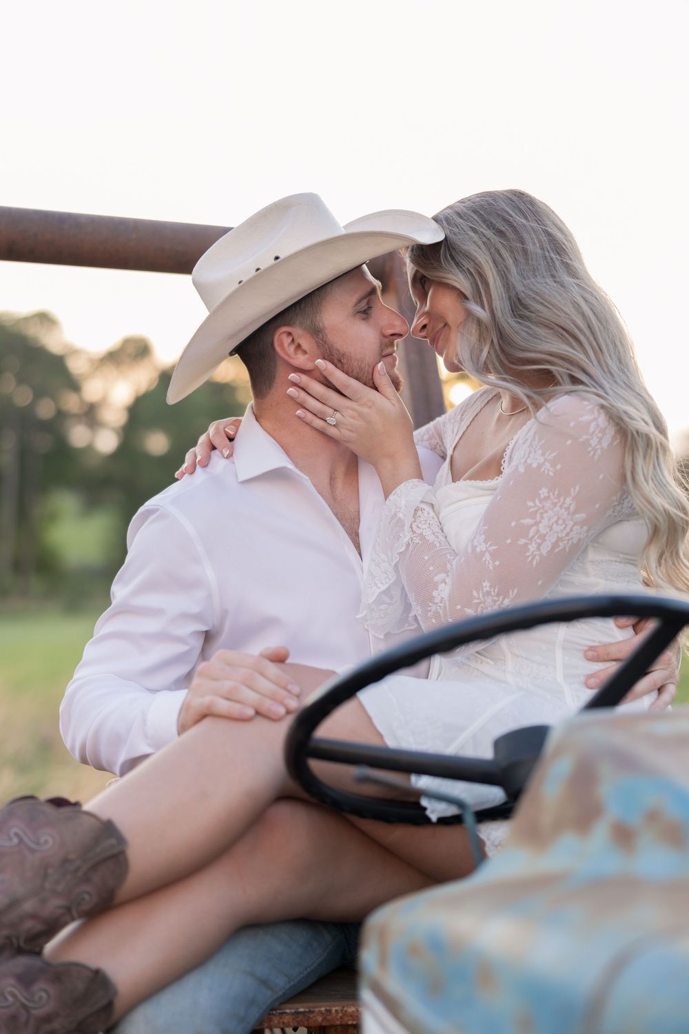 Romantic couple shares an intimate moment sitting in a vintage truck at sunset with cowboy boots and western attire.