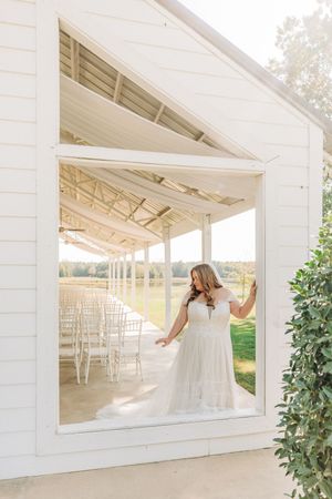 Elegant white wedding venue with French doors and covered porch area set against lush greenery and natural light.
