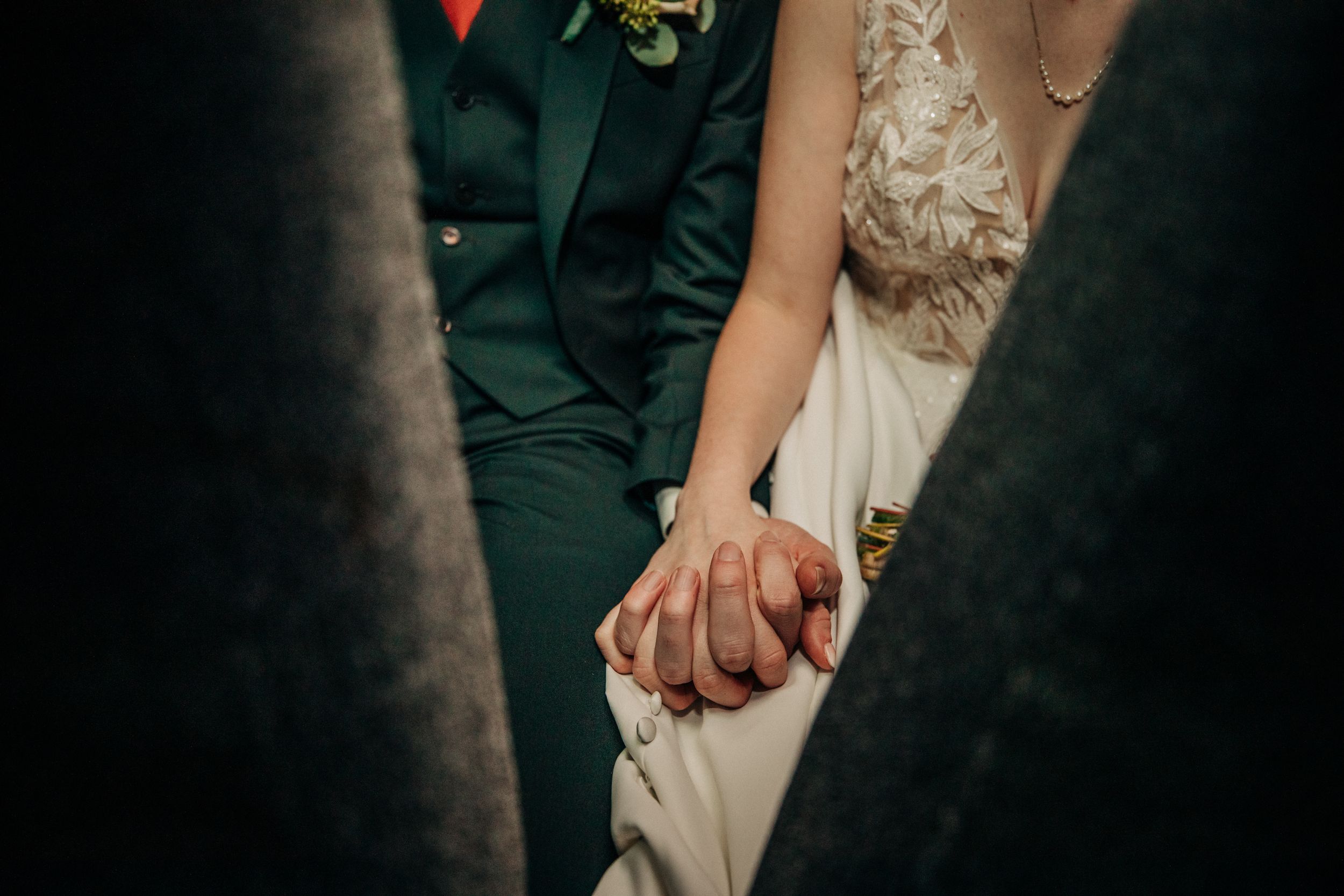 Close-up shot of two people holding hands during a wedding ceremony between a bride and military service member.