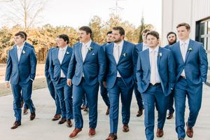 Wedding party wearing navy blue suits walks together on paved path during autumn.