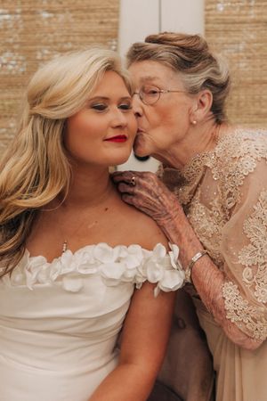 A tender moment between a bride in a white ruffled dress and an elderly woman wearing a beaded lace dress.