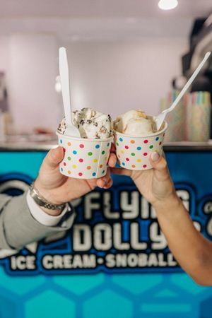 Person eating polka dot cups of ice cream while sitting at "Dolly's" ice cream shop counter.