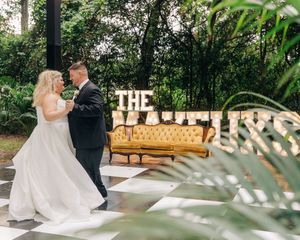 Elegant wedding couple embraces on a lush garden pathway during their romantic outdoor ceremony.