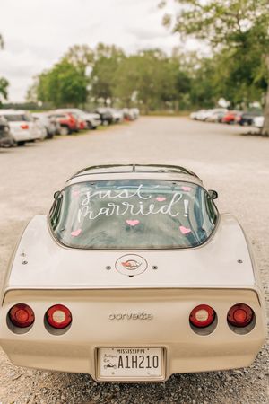 A series of close-up shots showing 'just married' written on the back of a classic cream-colored Corvette.