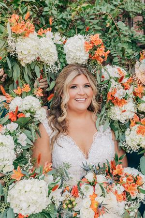 Beautiful floral arrangement with white hydrangeas and orange lilies creating a frame of colorful wedding flowers.