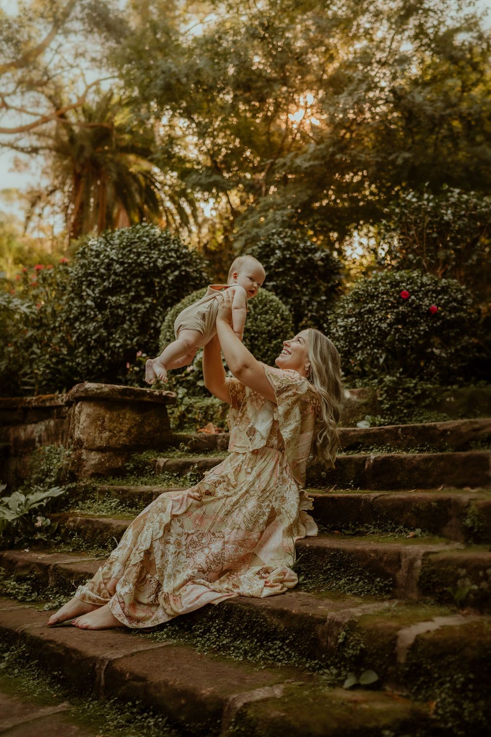 A joyful moment on stone garden steps during golden hour sunset as sun filters through trees and greenery.