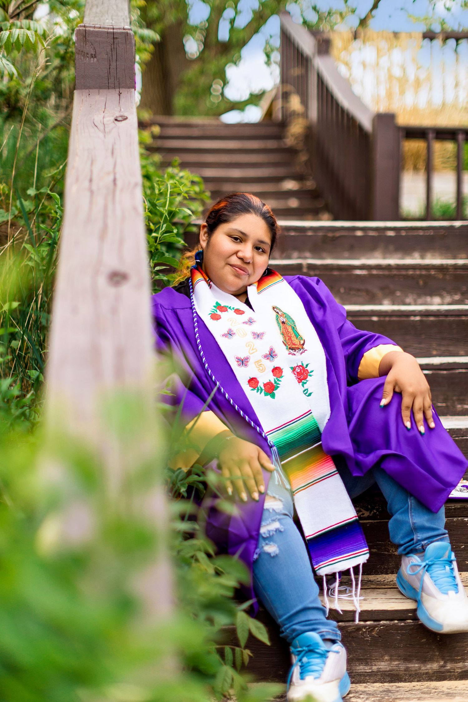 lejandra, Class of 2025, sitting mid-staircase at Van Buren Street Beach Access in South Haven, Michigan, smiling gently