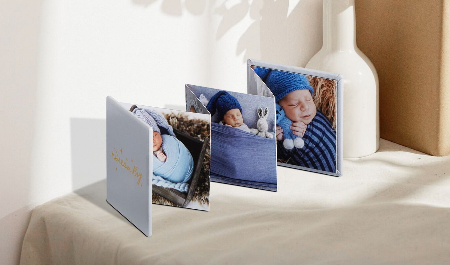 Photo album of square photographs arranged in an accordion-style display on a light colored surface with soft lighting.