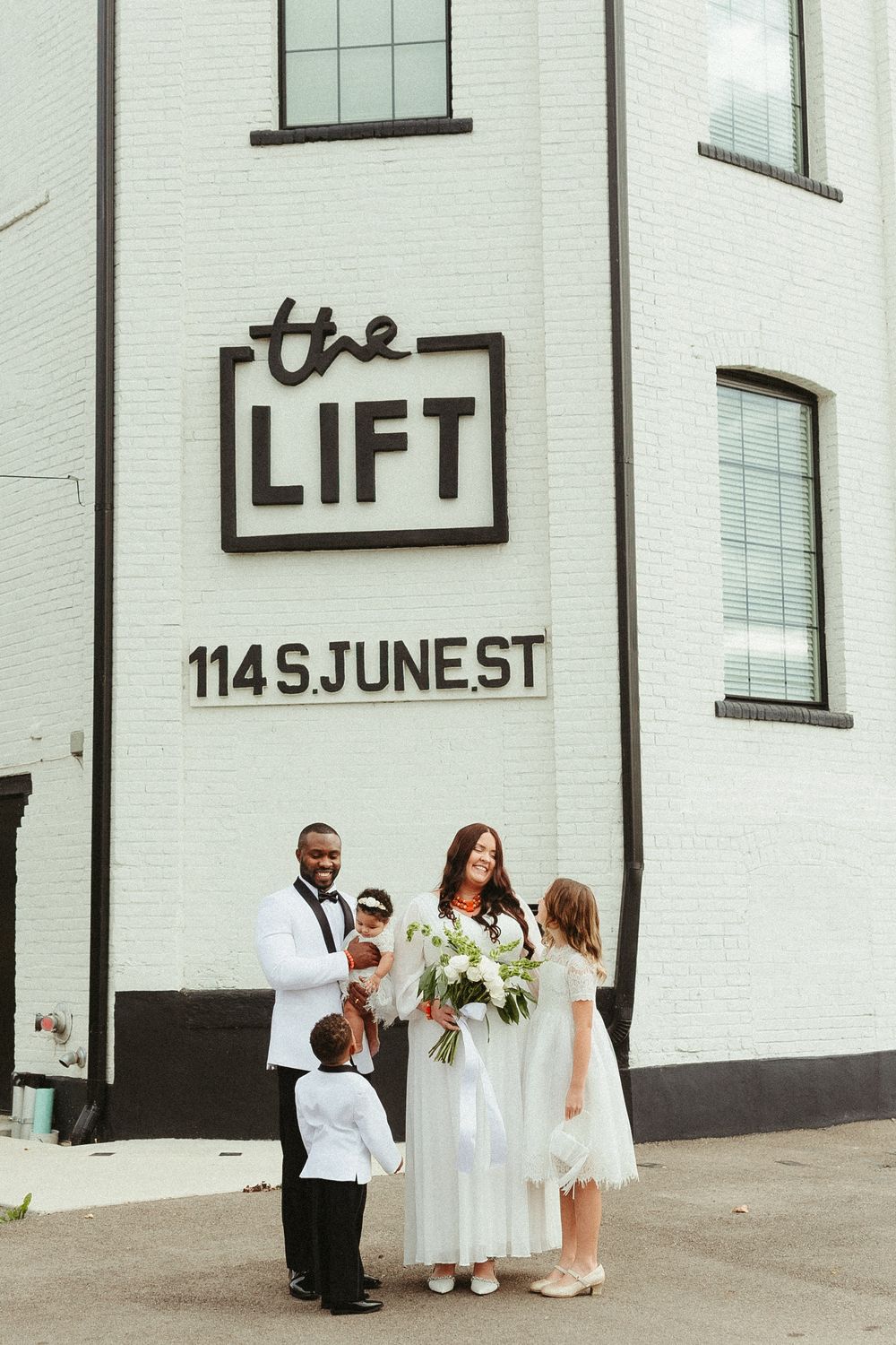 A group stands outside The Lift building at 114 S June St, with white exterior walls and windows.