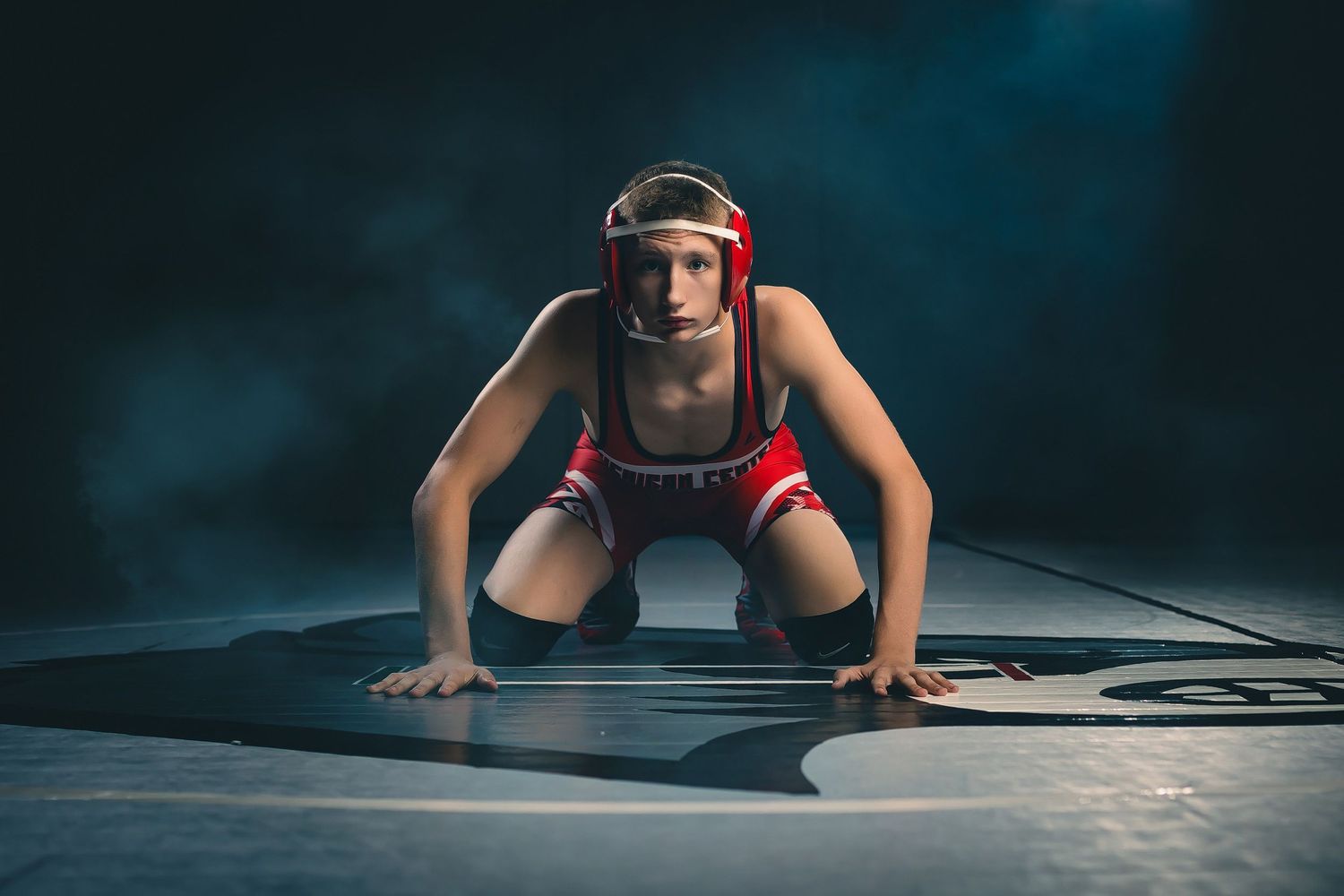 Dramatic athletic pose on mat in dark lighting with workout gear.