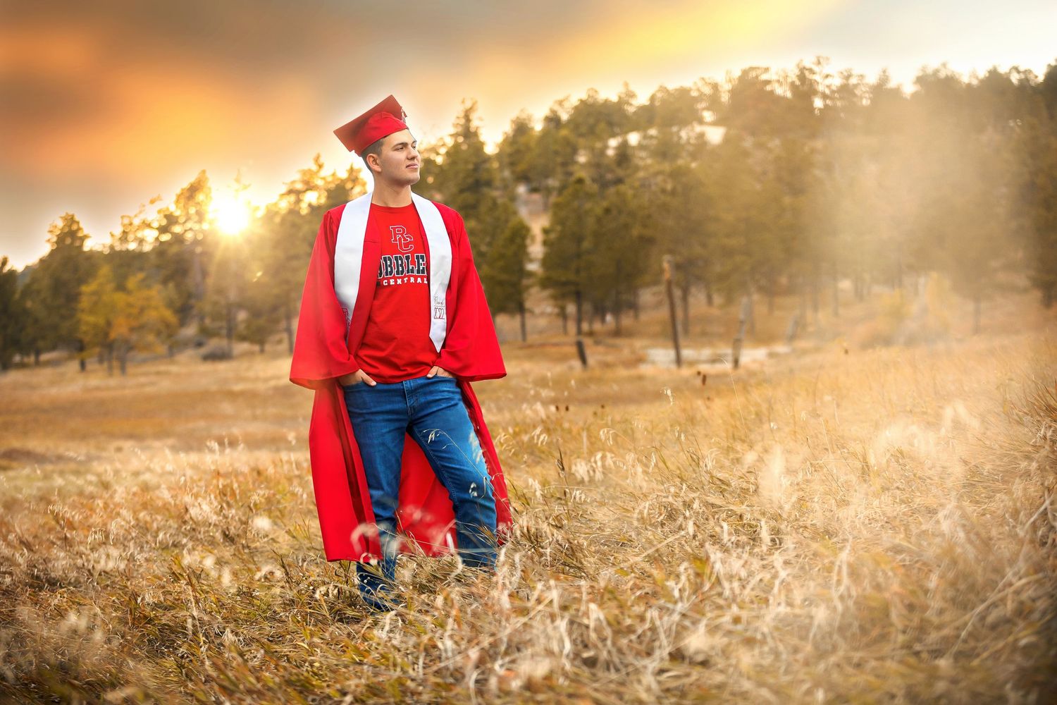 Person in red clothing sits among autumn grass at golden hour.