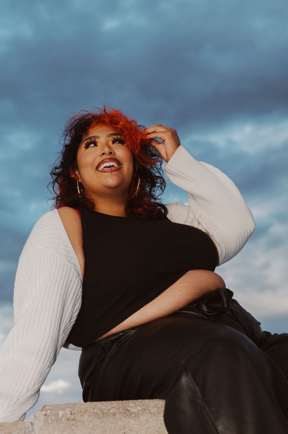 Fashion portrait taken outdoors against dramatic cloudy sky featuring person in black and white contrast clothing.