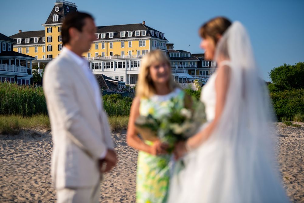A coastal wedding ceremony on a beach with historic seaside hotels in the background on a sunny day.