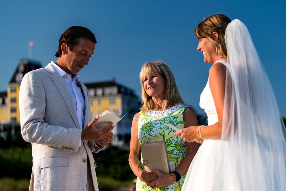 Outdoor wedding ceremony takes place against a blue sky and yellow building backdrop during golden hour.