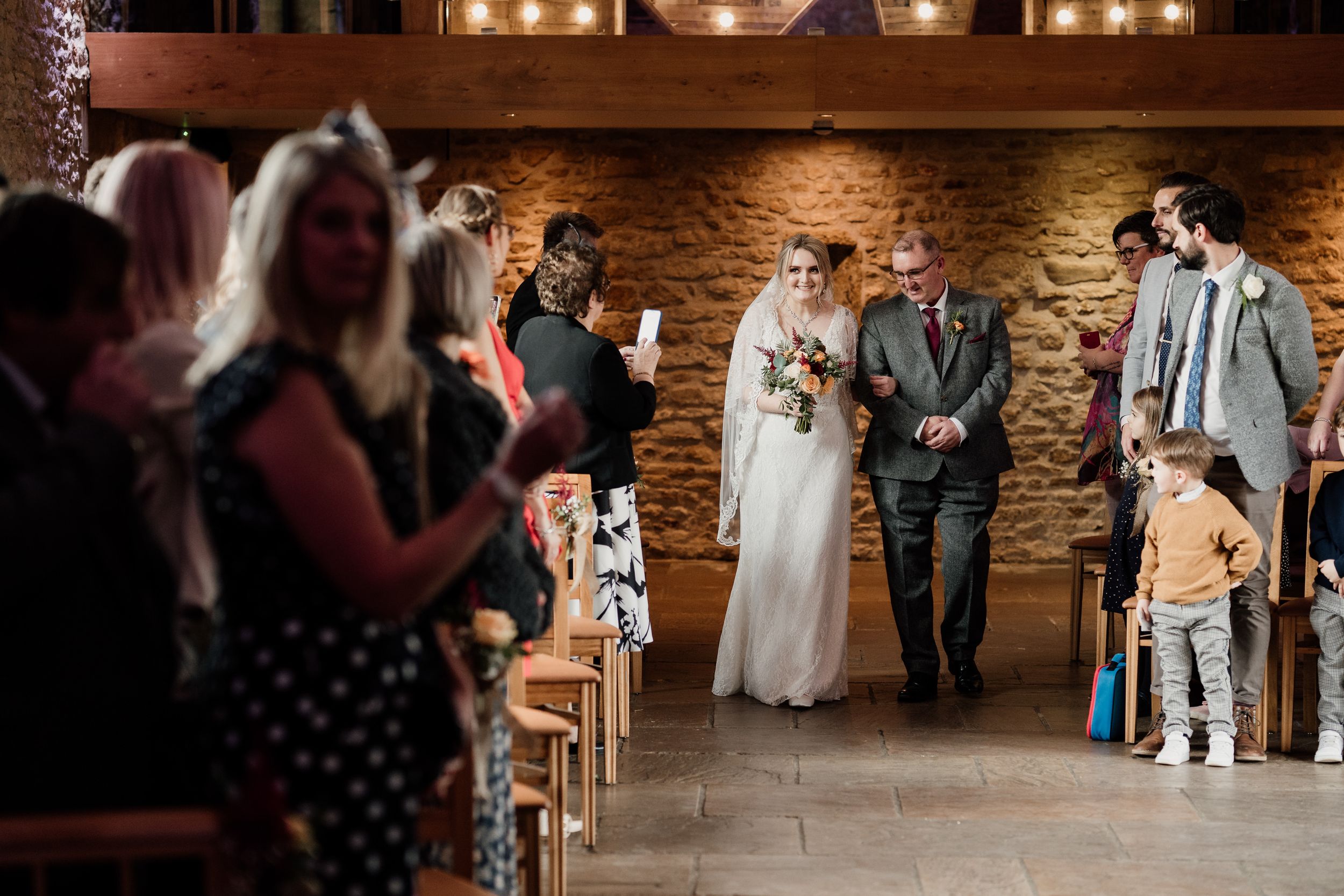 Wedding ceremony taking place in a rustic brick-walled venue with warm lighting.