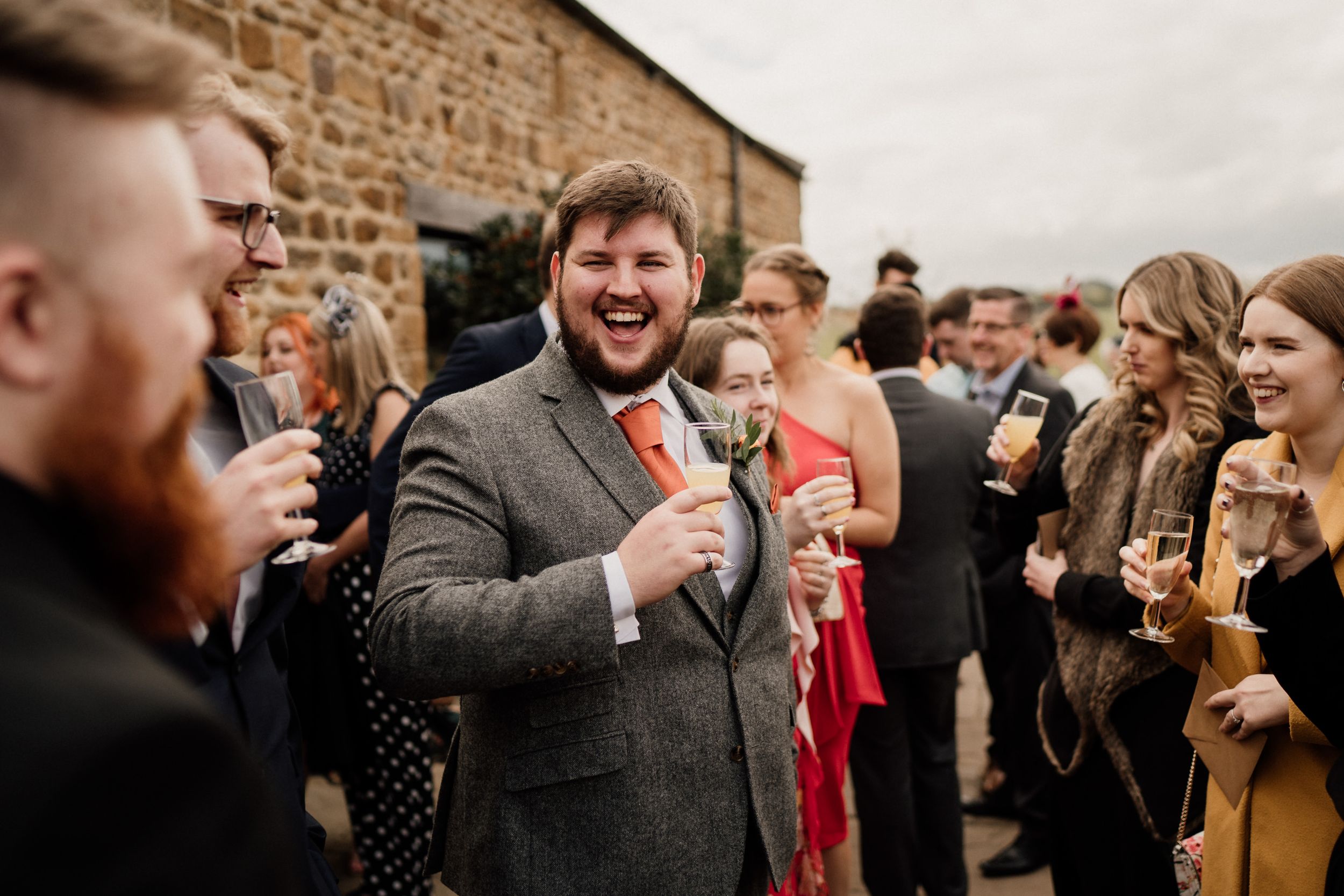 Wedding guests enjoying drinks and celebrations outside rustic venue.