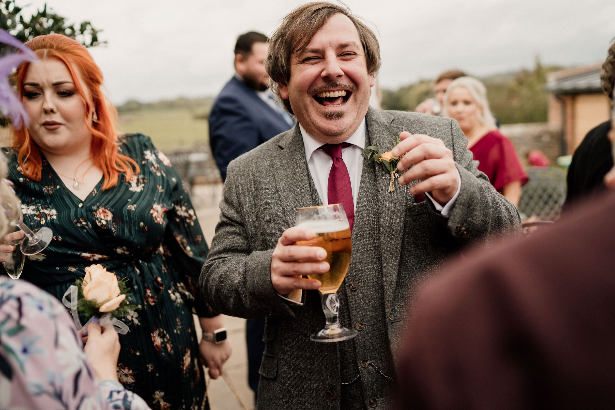Wedding guests socializing and laughing during outdoor reception festivities.