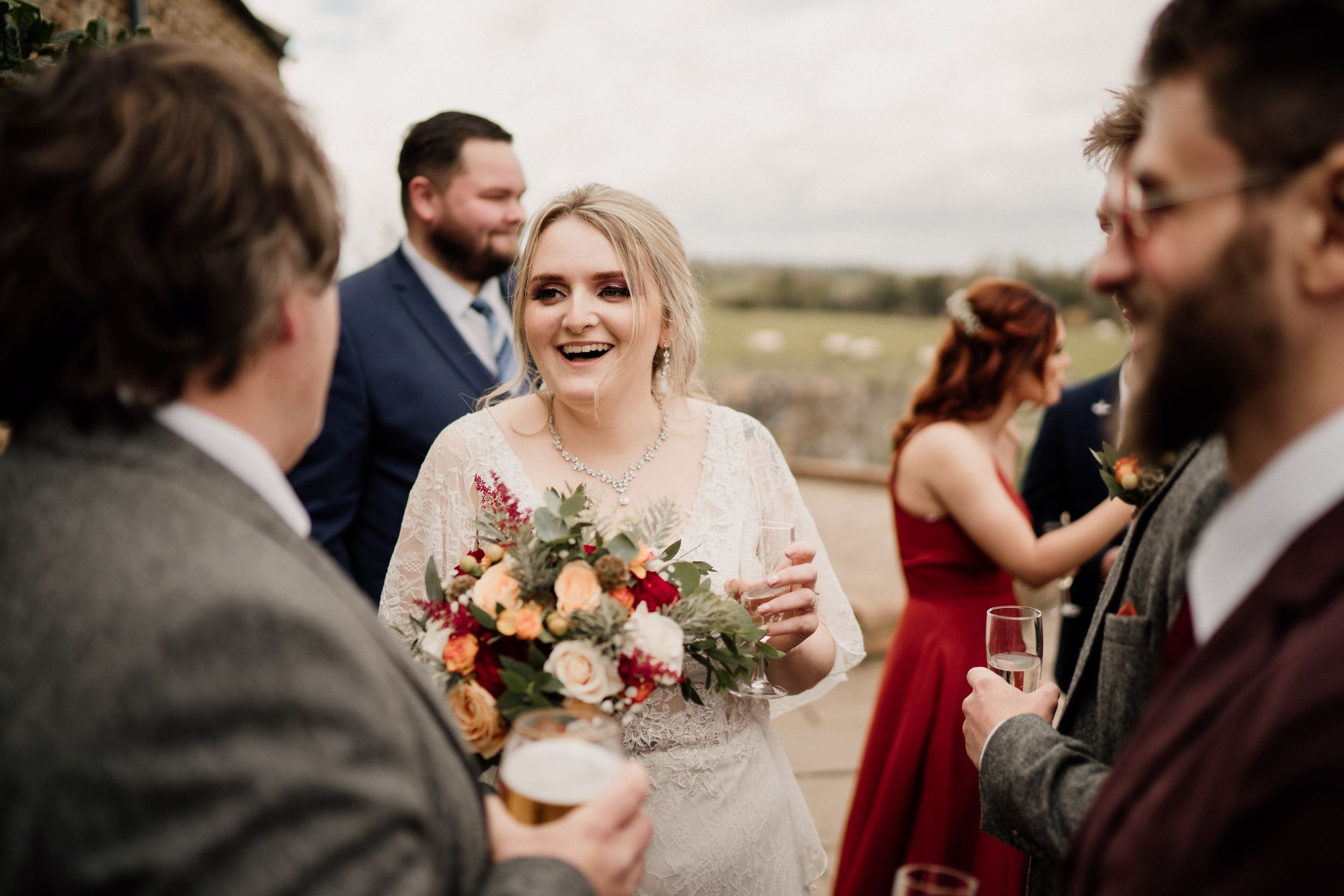 A joyful wedding reception moment outdoors with guests mingling and a beautiful bouquet of flowers.
