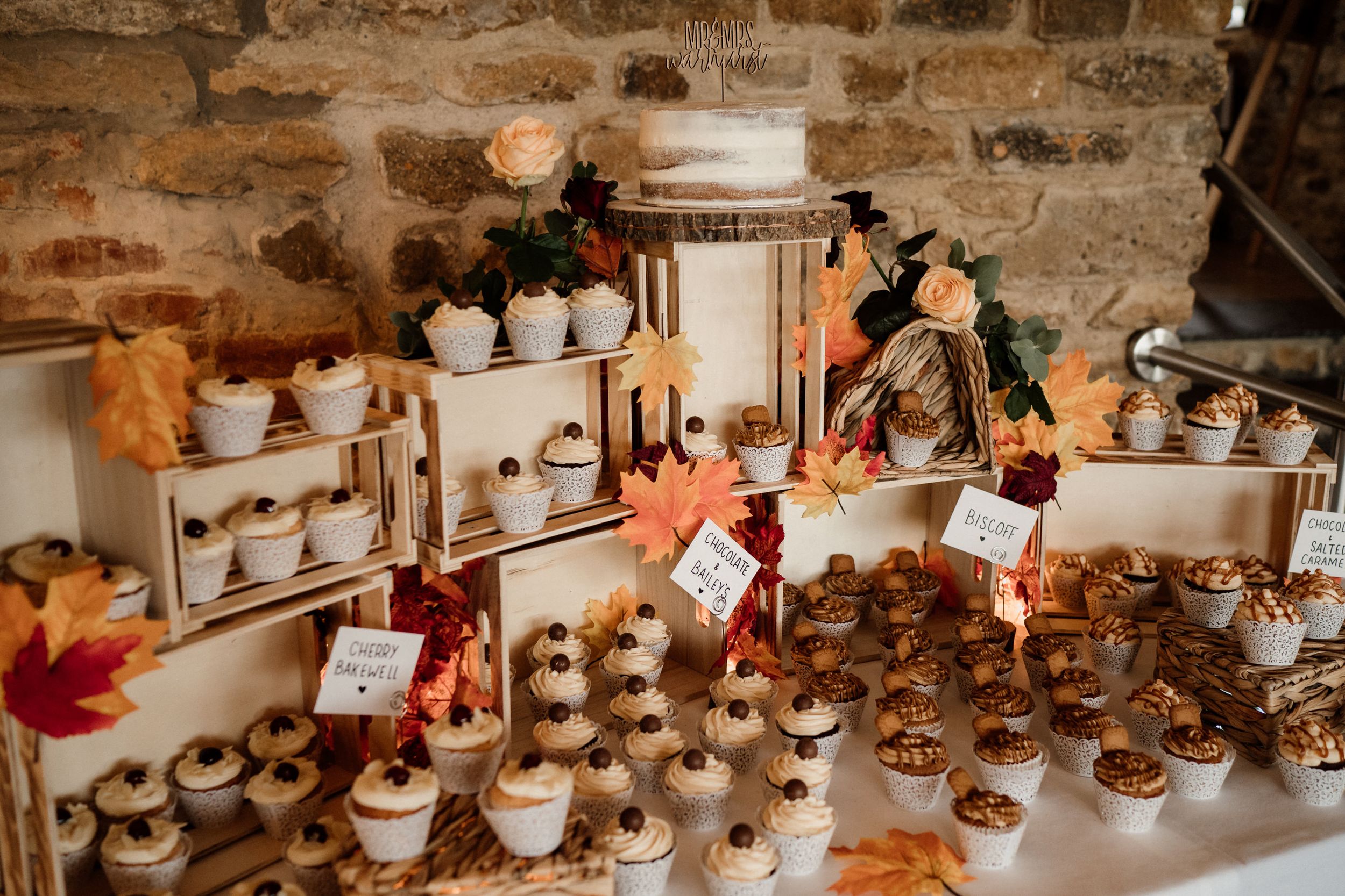 Rustic dessert display with cupcakes and autumn decorations on wooden crates.
