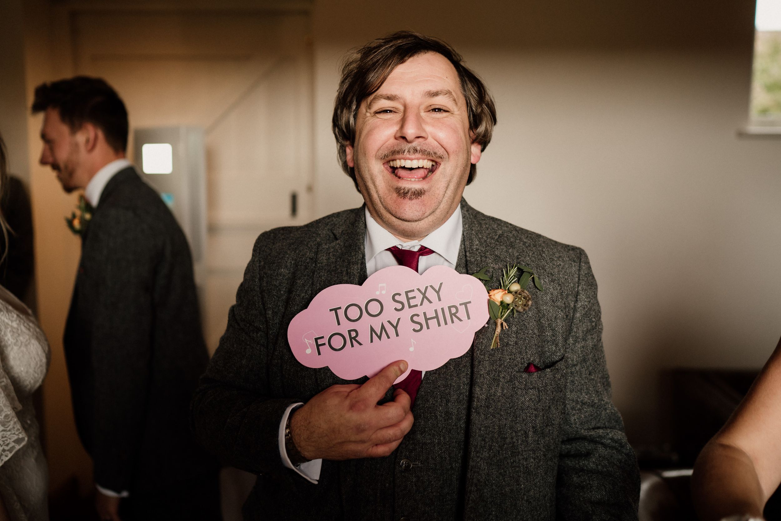 Wedding guest holding pink heart-shaped sign at indoor celebration.