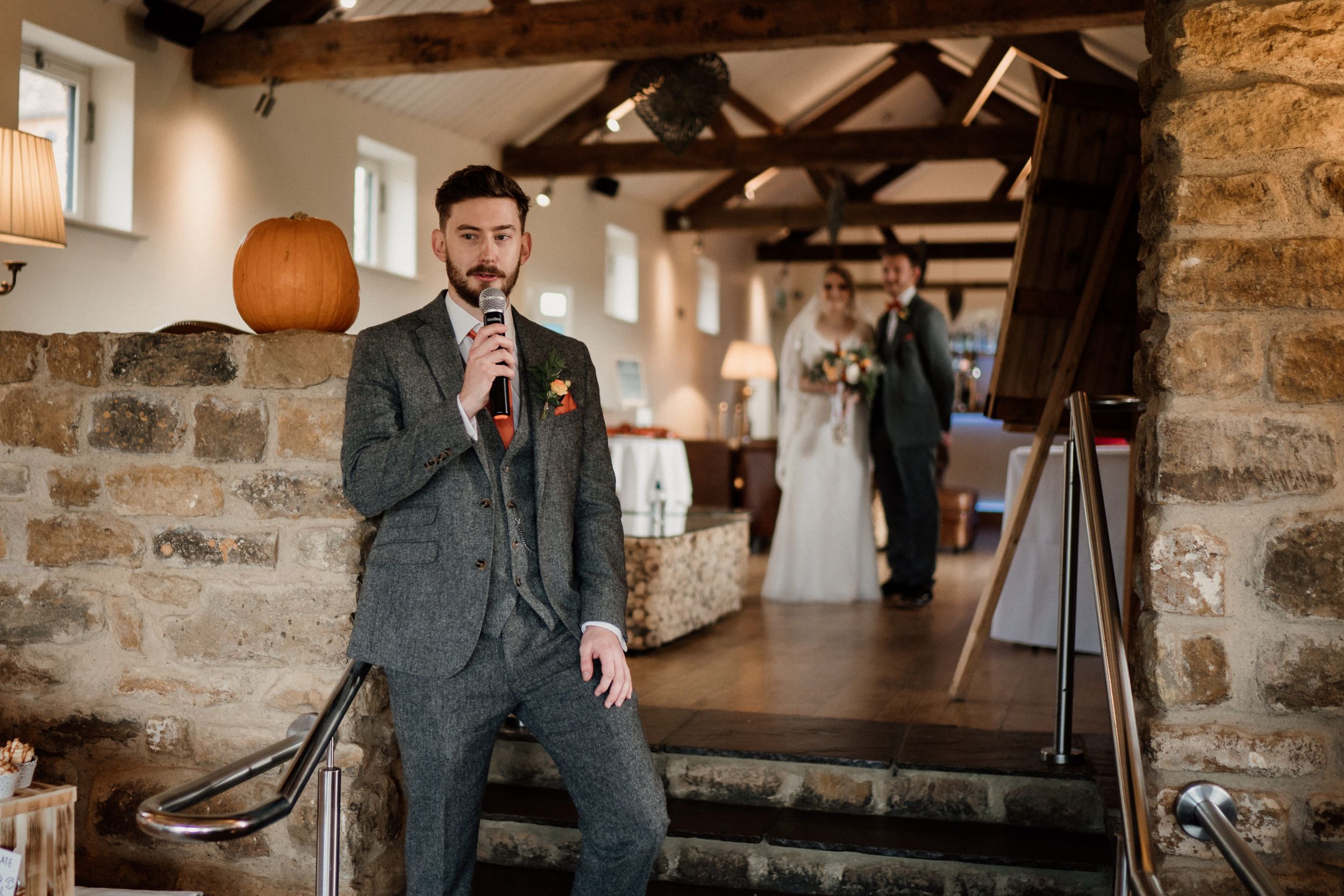 Wedding ceremony setup in rustic stone venue with exposed wooden beams.